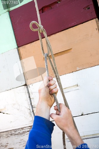 Image of Beekeeper's Hand Tying Rope On Honeycomb Crates