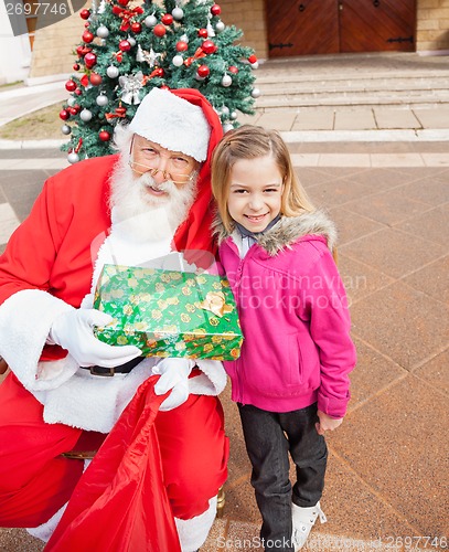 Image of Girl And Santa Claus Holding Gift