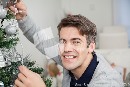 Image of Man With Fairy Lights Decorating Christmas Tree