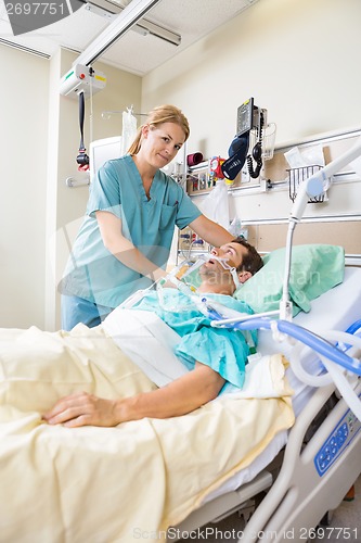 Image of Nurse Adjusting Patient's Pillow In Hospital