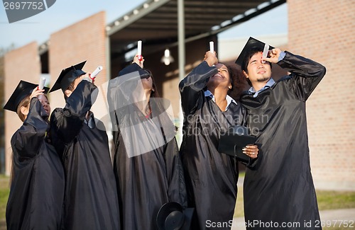 Image of Students In Graduation Gown Looking Through Certificates On Camp