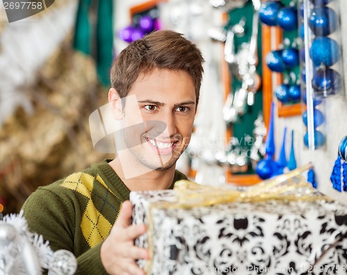 Image of Man Holding Christmas Present In Store