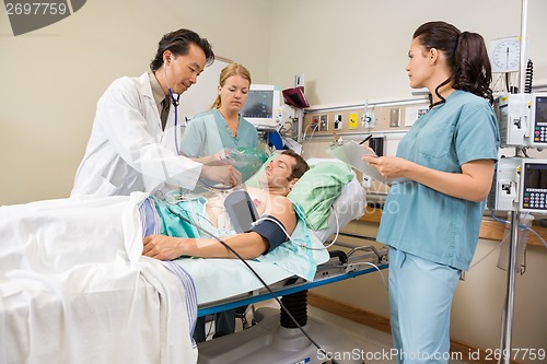 Image of Nurses And Doctor Examining Male Patient