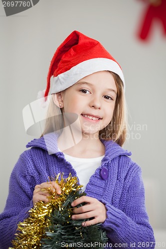 Image of Smiling Girl Holding Tinsels During Christmas