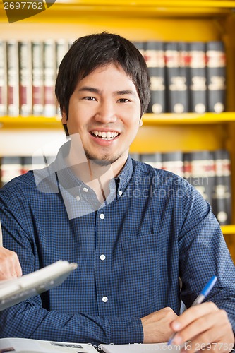 Image of Male Student Sitting Against Bookshelf In University Library