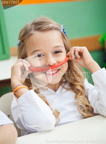 Image of Girl Holding Mustache Made Of Clay In Preschool