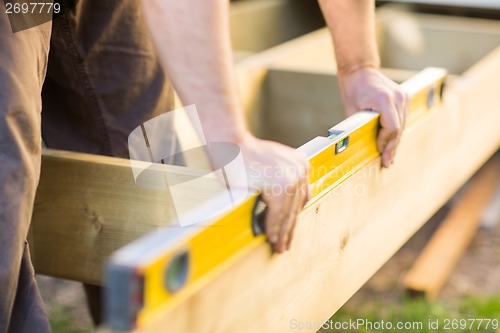 Image of Carpenter's Hands Checking Level Of Wood At Site