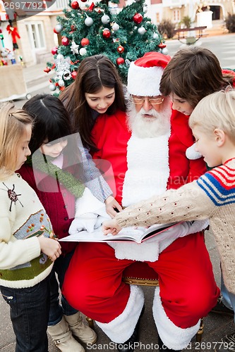Image of Santa Claus With Children Pointing At Book