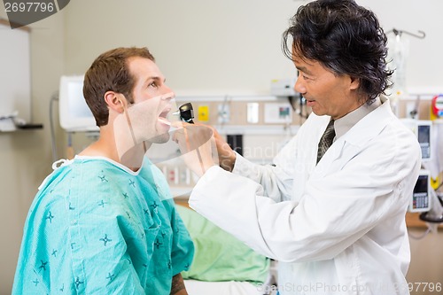 Image of Doctor With Depressor And Otoscope Checking Patient's Mouth