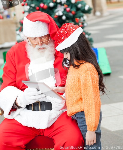 Image of Girl And Santa Claus Using Digital Tablet