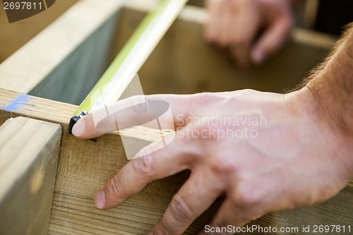 Image of Carpenter's Hand Measuring Wood With Tape