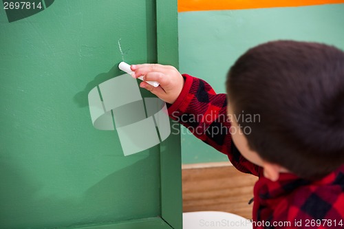 Image of Boy Writing On Green Chalkboard In Preschool