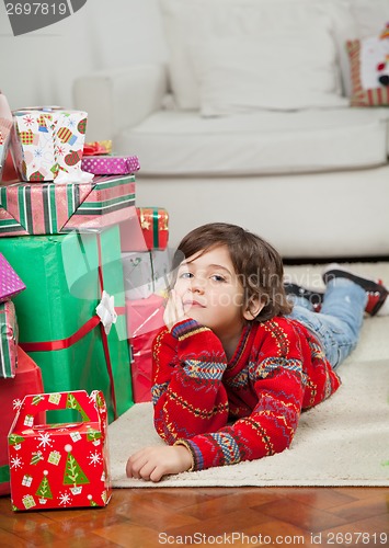 Image of Boy Lying Besides Stacked Presents