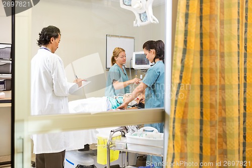 Image of Nurses And Doctor Examining In Patient