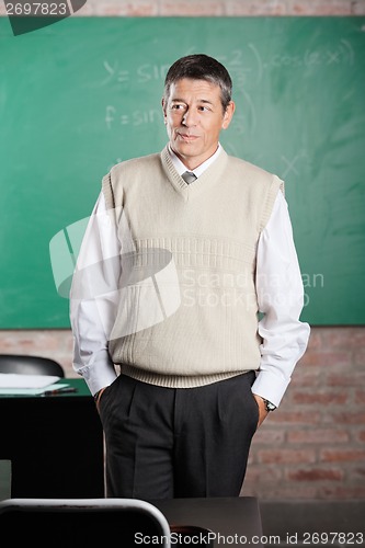 Image of Teacher With Hands In Pockets Looking Away In Classroom