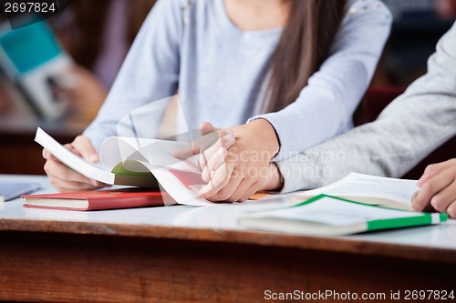 Image of Teenage Couple Holding Hands At Table In Library