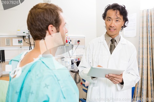 Image of Doctor Holding Digital Tablet By Patient In Hospital