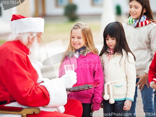 Image of Santa Claus Offering Biscuits And Milk To Children