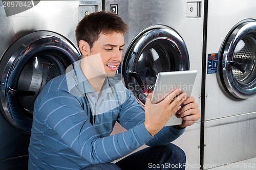 Image of Man Using Digital Tablet At Laundry