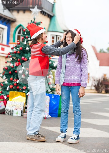 Image of Boy Putting Santa Hat On Girl's Head