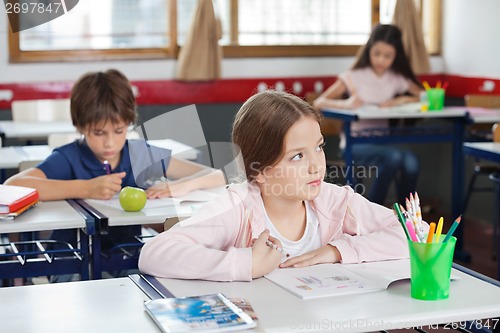 Image of Schoolgirl Looking Away While Drawing In Classroom