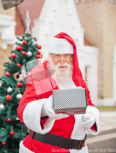 Image of Santa Claus Giving Gift Against House