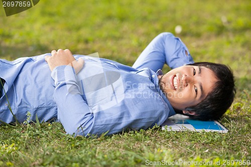 Image of Male Student Lying On Grass At College Campus