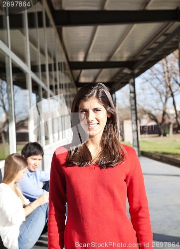 Image of Woman Smiling With Students In Background On Campus