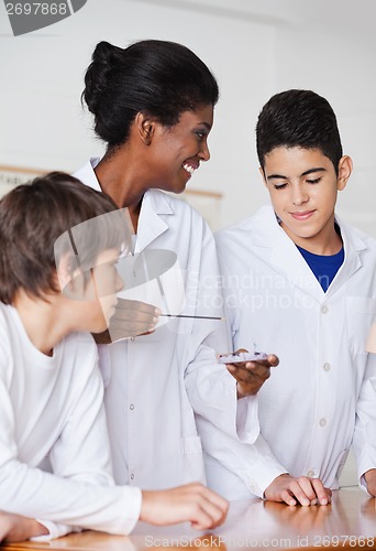 Image of Teacher Looking At Student While Experimenting At Desk