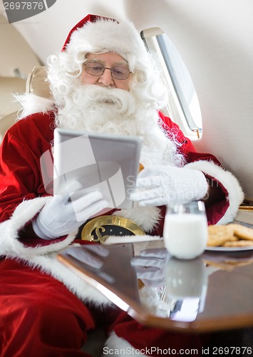 Image of Santa Using Digital Tablet In Private Jet