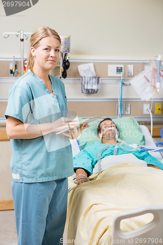 Image of Nurse With Digital Tablet While Male Patient Resting On Bed