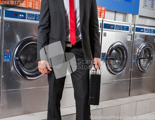 Image of Businessman Holding Suitcase In Laundry