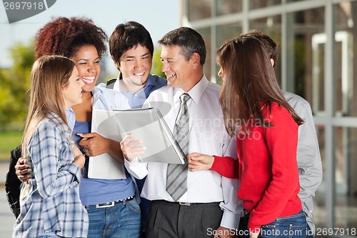 Image of Students And Teacher With Book Standing On University Campus