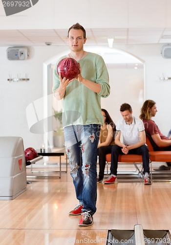 Image of Young Man Holding Bowling Ball in Club