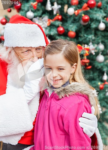 Image of Santa Claus Whispering In Cute Girl's Ear