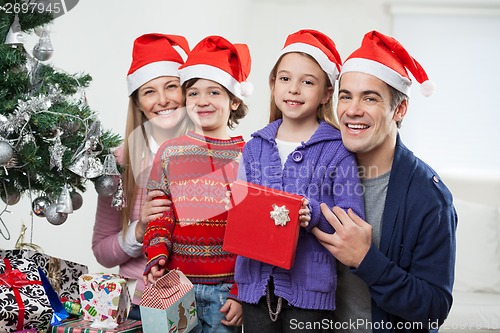 Image of Family In Santa Hats With Christmas Present