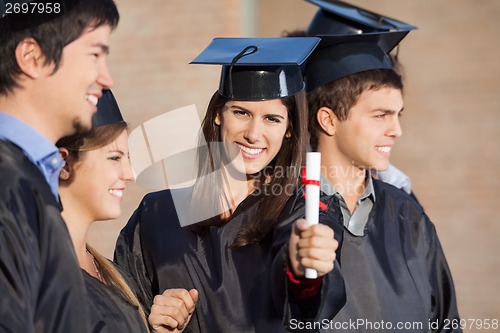 Image of Student Showing Diploma While Standing With Friends At College