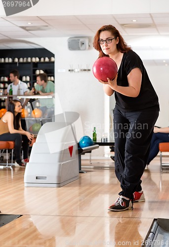 Image of Young Woman Playing in Bowling Alley At Club