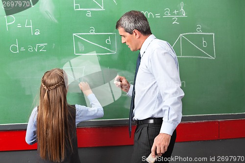 Image of Girl Drawing Geometric Shapes On Board With Teacher Assisting He