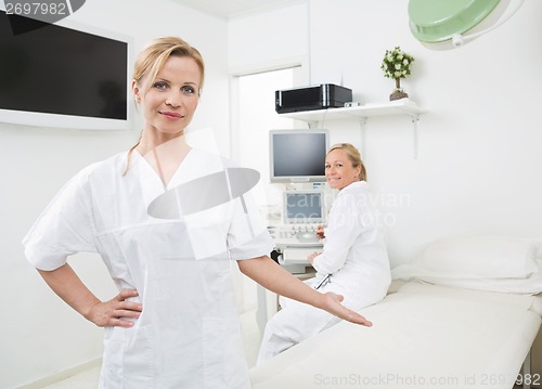 Image of Gynecologist Gesturing With Colleague In Background