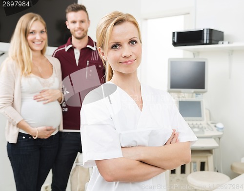 Image of Confident Gynecologist With Expectant Couple In Background