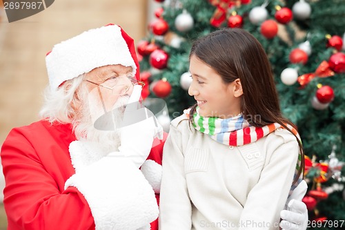 Image of Santa Claus Gesturing Finger On Lips At Girl