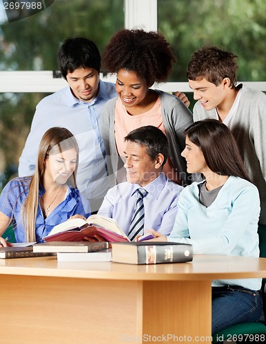 Image of Professor Explaining Students At Desk In Classroom