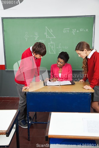 Image of Female Teacher Teaching Teenage Students At Desk