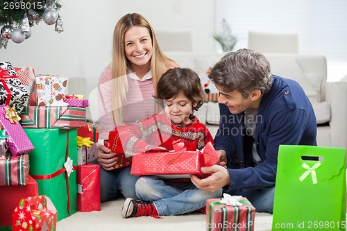 Image of Woman With Boy And Man Opening Christmas Gift