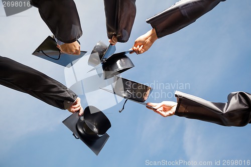 Image of Students Raising Mortar Boards Against Sky On Graduation Day