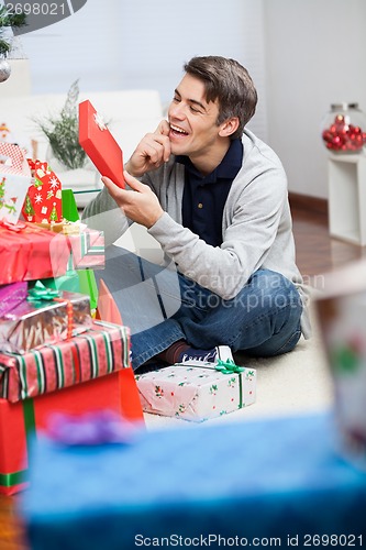 Image of Man Looking At Christmas Gift In House