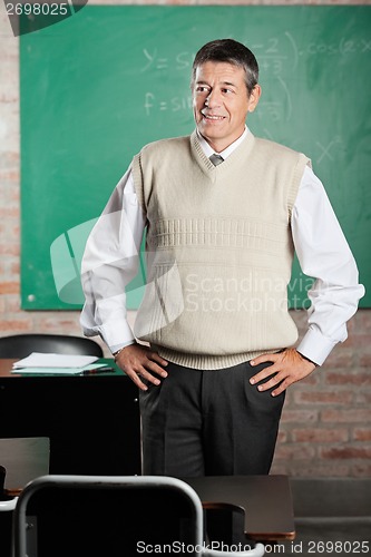 Image of Teacher With Hands On Hips Looking Away In Classroom