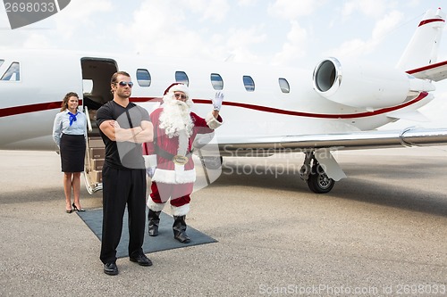 Image of Santa Waving Hand Against Private Jet