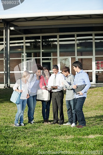 Image of Students With Teacher Discussing Over Book On Campus